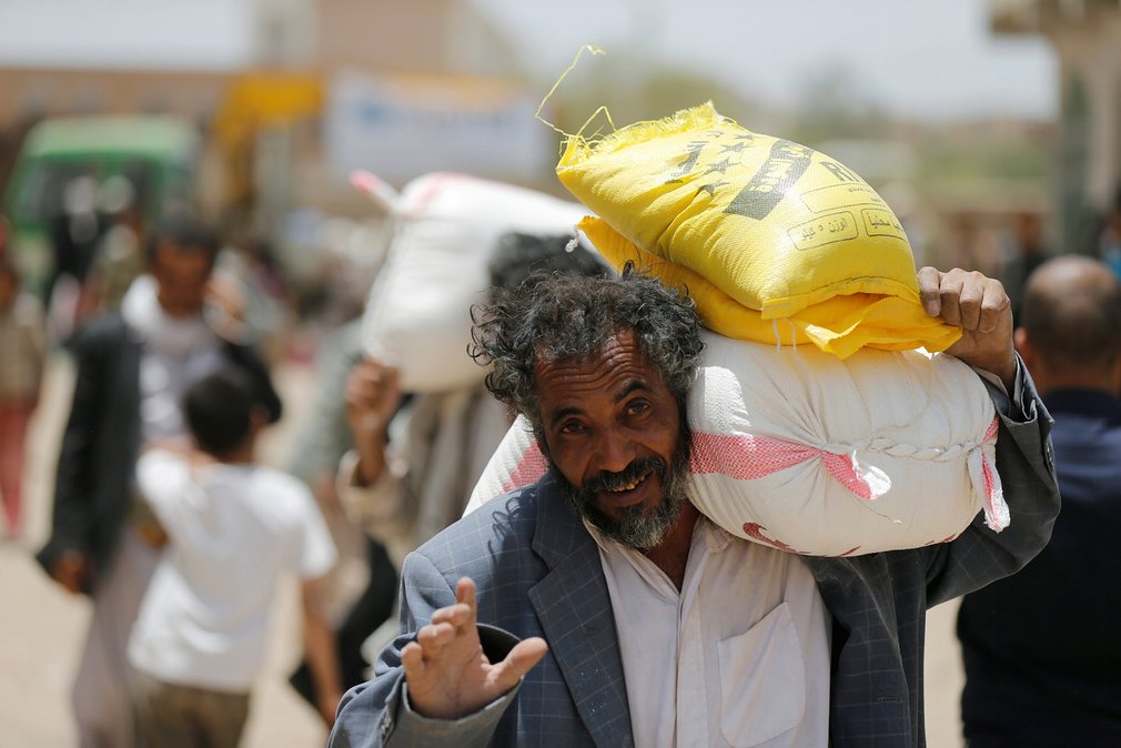 مرد یمنی در حال حمل کیسه های گندم و برنج و شکر که توسط یک خیریه بین مردم پخش شده است