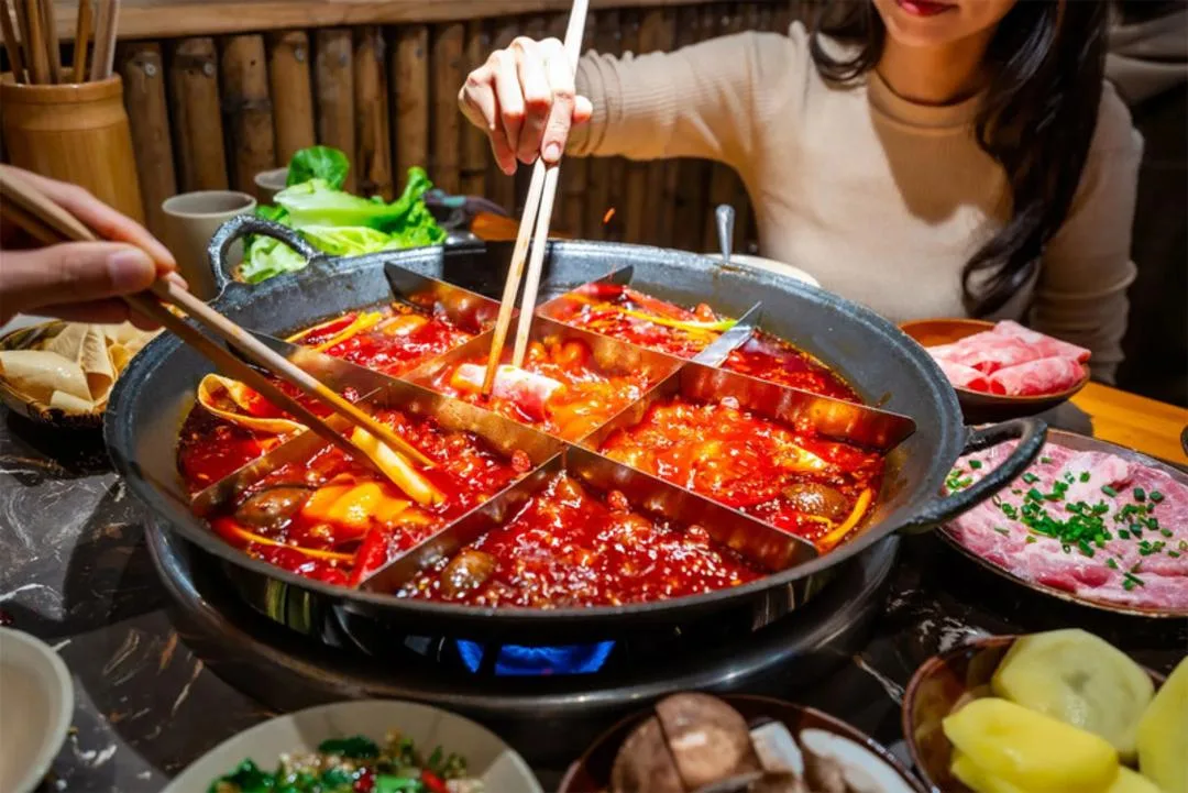 دیگ هاتپات (Hotpot) پر از سوپ تند و مواد غذایی متنوع