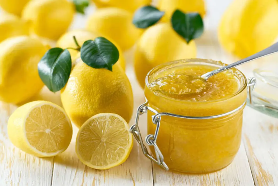 مربای لیمو (Lemon Jam) در ظرف شیشه‌ای در کنار لیموی تازه