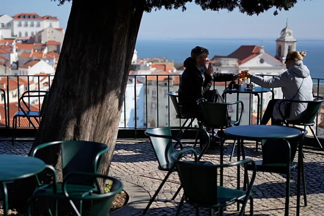 دو نفر در کافه ای با منظره شهر لیسبون (Lisbon) نشستهاند