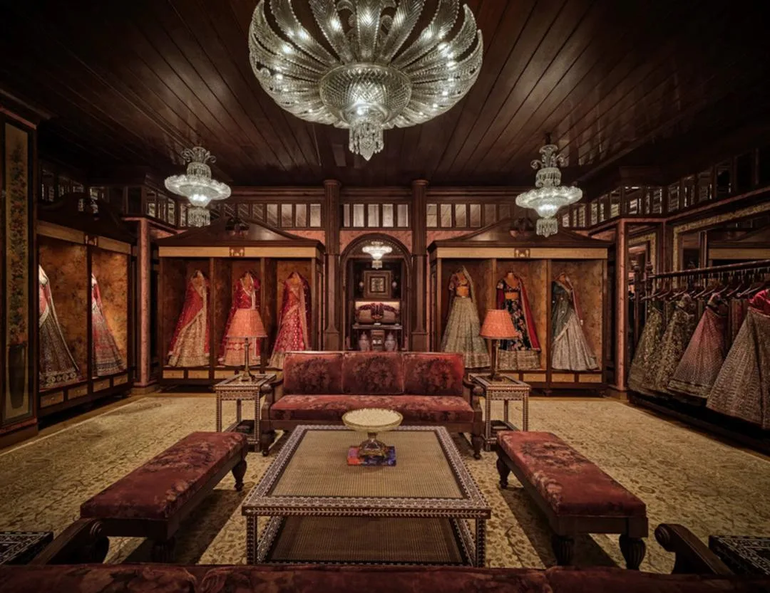 نمای داخلی فروشگاه سابیاساچی (Sabyasachi) با لوستر بزرگ و لباسهای سنتی